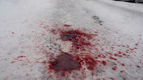 Dunkelrotes-Blut-Auf-Verschneiter-Straße,-Autos-Nach-Unfall-Im-Hintergrund