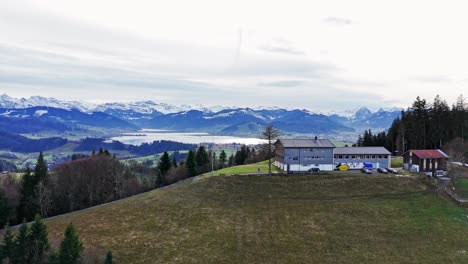 Aerial-View-of-swiss-town-Einsiedeln-and-lake-Sihlsee,-snowy-mountains