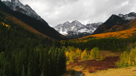 Colorful-Colorado-cinematic-aerial-drone-Aspen-Maroon-Bells-Capital-Peak-wilderness-14ers-autumn-fall-Aspen-Trees-first-snow-cloudy-sunny-morning-dramatic-incredible-landscape-forward-pan-up-motion