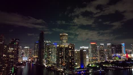 Above-Miami's-evening-skyline,-an-airplane-gracefully-glides,-accentuating-the-illuminated-downtown-skyscrapers