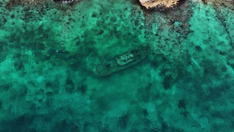 Die-Drohne-Fliegt-Um-Ein-Schiffswrack-Im-Meer-Herum,-Wo-Menschen-In-Curaçao-Luftaufnahmen-In-4K-Schnorcheln