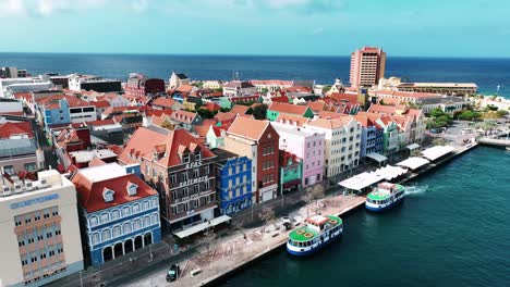 The-drone-is-flying-away-from-the-old-colorfull-houses-on-the-trade-quay-in-Willemstad-Curacao-Aerial-Footage-4K