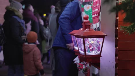 Ein-Kleiner-Junge-Beobachtet-Die-Weihnachts-Hängelampe,-Während-Er-Im-Park-Im-Rahmen-Der-Galati-Feier-Zum-Nationalfeiertag-In-Rumänien-Zuckerwatte-Isst-–-Mittlere-Aufnahme