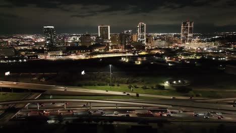 Fort-Worth,-Texas-skyline-at-night-with-drone-video-circling-showing-freeway