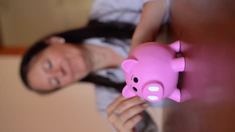 Vertical-Shot-Of-Woman-Putting-Coins-On-Piggy-Bank