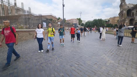 Rome-Immersive-POV:-Moving-In-Busy-Streets-to-Chiesa-Santi-Luca-e-Martina,-Italy,-Europe,-Walking,-Shaky,-4K-|-Traveler-Crowd-Near-Colosseum