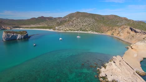 Drone-video-flying-into-a-beautiful-protected-bay-of-clear-blue-water-in-a-tropical-paradise-along-the-coast-of-a-rocky-peninsula