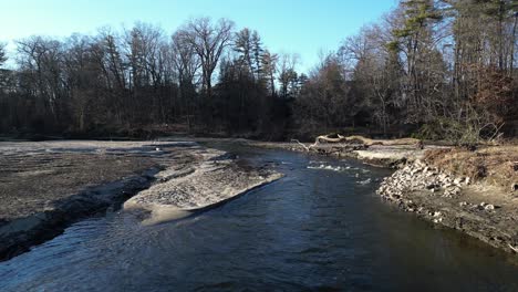 Backward-shot-of-a-river-flow-that-is-badly-eroded-with-a-dry-trees