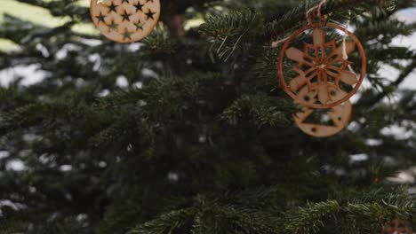 Hölzerne-Weihnachtsdekorationen-Auf-Grünem-Weihnachtsbaum,-Schwenk-Nach-Unten,-4K