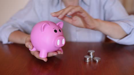 Hand-Inserting-Coins-On-Piggy-Bank---Concept-of-Saving-Money