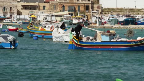 Pescador-Conduciendo-Su-Pequeño-Y-Colorido-Barco-A-Motor-En-El-Puerto-De-Marsaxlokk