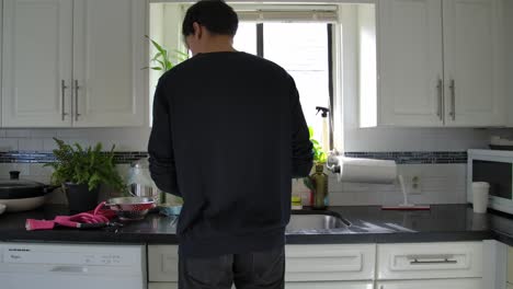 Hombre-Lavando-Los-Platos-En-La-Cocina