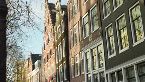 Pedestrians-walking-along-typical-streets-of-Amsterdam-with-traditional-old-houses,-Netherlands