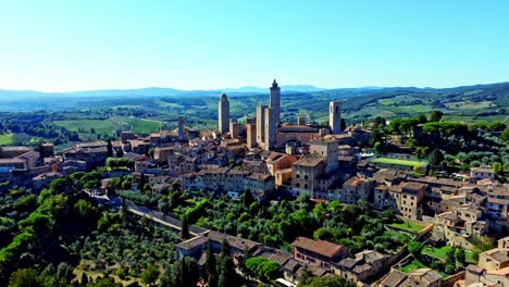 Backward-drone-shot-of-the-town-of-San-Gimignano,-Tuscany,-Italy-with-its-famous-medieval-tower