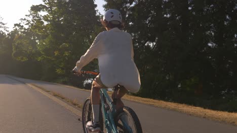 Ciclista-Con-Casco-Montando-Bicicleta-En-El-Parque-Durante-La-Puesta-De-Sol