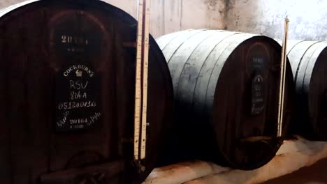 Wine-aging-in-dark-wooden-barrels-stored-in-warehouse-in-Vila-Nova-de-Gaia,-Portugal