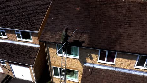 Man-cleaning-a-house-roof-with-soft-washing-technique