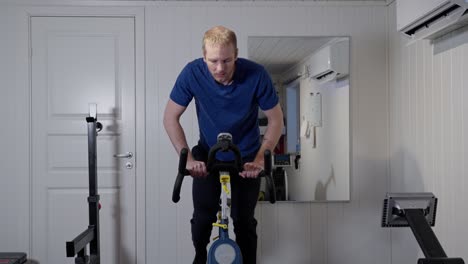 Middle-aged-caucasian-man-workout-on-bike-in-home-gym,-front-view