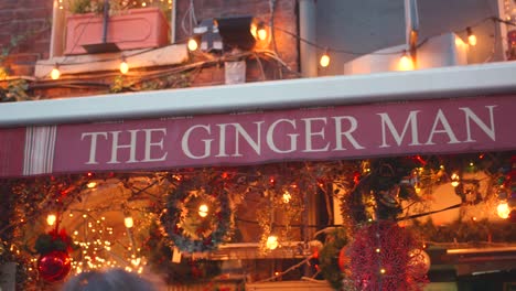 The-Ginger-Man-Irish-Pub-Entrance-Sign-Glowing-With-Christmas-Ornaments-And-Lights-In-Dublin,-Ireland