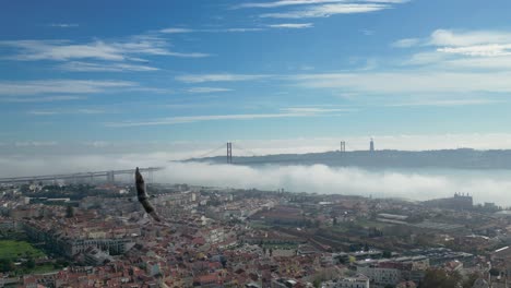 Aerial-view-of-the-Tagus-River-blanketed-in-fog,-with-the-iconic-Christ-the-Redeemer-statue-in-the-background,-creating-a-mystical-and-atmospheric-scene