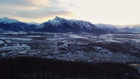 Salzburg-snow-covered-cityscape,-sideways,-establishing-with-Alps-behind