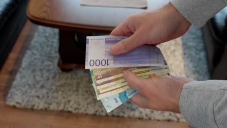 Man-counting-different-denominations-of-Norwegian-Krone,-slow-motion