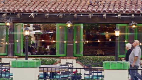 Große-Stabile-Aufnahme-Von-Menschen,-Die-In-Einem-Restaurant-In-Der-Innenstadt-Von-Palm-Springs,-Kalifornien,-Essen,-Mit-Vorbeigehenden-Fußgängern-Und-Linseneffekt