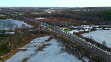 Road-intersection-with-roundabout-in-countryside-landscape-during-winter-season,-aerial-view