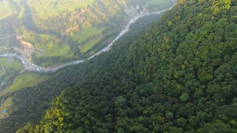 Dutch-angle-drone-shot-falls-through-valley-ridge-to-reveal-meandering-river-in-Pokhara-Nepal
