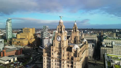 Liver-Bird-anti-clockwise-rotate---circled-by-drone-on-a-sunny-morning,-Liverpool-cityscape-backdrop