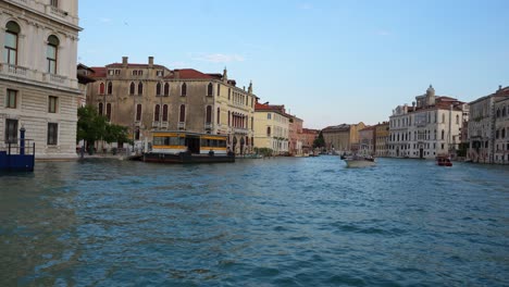 Traghetto-navigating-Venetian-canal-with-motorboats-and-gondolas,-heading-to-dock