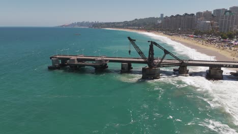 Aerial-View-Of-Vergara-Pier-In-Vina-Del-Mar-Jutting-Out-From-Beach-Into-Turquoise-Ocean-Waters