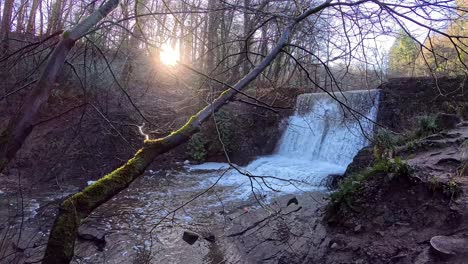 Sun-rising-over-waterfall-cascading-slow-motion-over-autumn-woodland-forest-stream