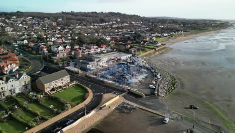 West-Kirby-Sailing-Club,-Wirral-on-a-sunny-morning---aerial-drone-clockwise-rotate-centring-on-boatyard-and-clubhouse