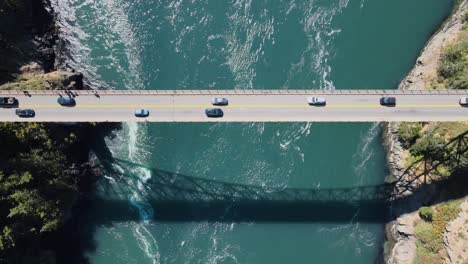Top-down-shot-of-vehicles-driving-across-Deception-Pass-with-a-river-running