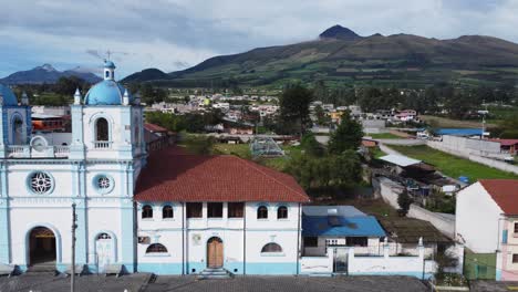 Aloasi-Kirche,-Blau-weiße-Fassade-Mit-Vulkanen,-Illizas-Und-Corazon-Im-Hintergrund