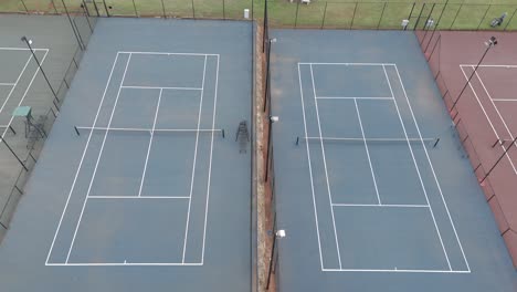 Slow-aerial-pan-above-old-empty-tennis-courts-with-different-colours