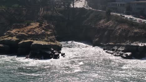 The-famous-La-Jolla-cove-and-shoreline-cliffs---pullback-aerial-reveal