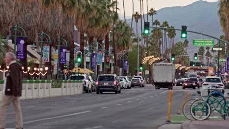 Tilt-down-from-Mountain-View-and-palm-trees-to-traffic-and-pedestrians-in-downtown-Palm-Springs,-California