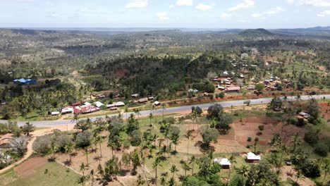Vista-Circular-De-Drones-Sobre-Un-Pequeño-Pueblo-Y-Palmeras-Junto-A-La-Carretera-De-Mombasa.