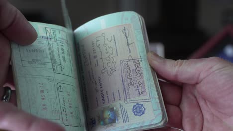 Man-hold-his-US-Passport-full-of-foreign-travel-visas---flipping-through-pages