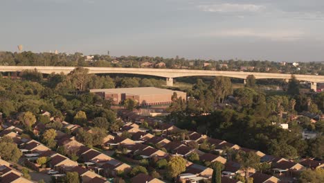 Slow-rotating-drone-footage-of-the-speed-train-bridge-and-houses-in-centurion,-South-Africa