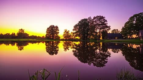 Zeitraffer-Eines-Farbenfrohen-Sonnenuntergangs-über-Einem-Haus-An-Einem-Ruhigen,-Sich-Spiegelnden-See