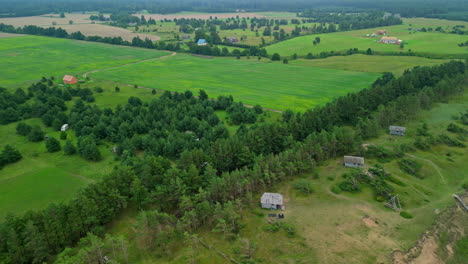 Aerial-open-green-field-next-to-river-and-forest-trees-in-summer