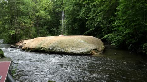 Eine-Kleine-Quelle-Entspringt-Einem-Felsen-Inmitten-Eines-Flusses-Und-Eines-Waldes