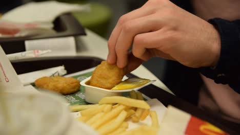 Man-dipping-nuggets-in-McDonalds-sauce-close-up