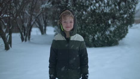 Junger-Glücklicher-Junge,-Der-Draußen-Lächelt,-Während-Er-Im-Winter-Im-Schnee-Spielt
