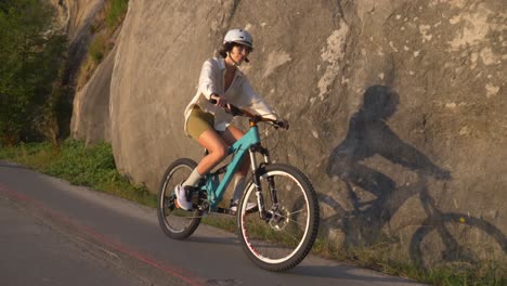 Mujer-Ciclista-Deportiva-Con-Casco-En-Una-Carretera-Durante-La-Puesta-De-Sol
