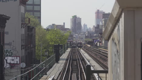 Two-Trains-Pulling-At-outdoor-subway-station-with-Brooklyn-in-Background