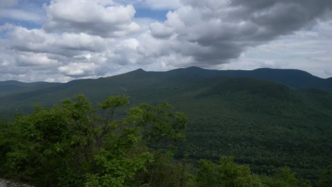 Ein-Schwenk-Von-Einem-Felsigen-Berggipfel-In-New-Hampshire-Zeigt-Eine-Mit-Vegetation-Bedeckte-Bergkette-Unter-Dichten-Wolken